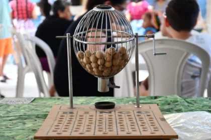Lottery draw cage filled with numbered wooden balls above a bingo board
