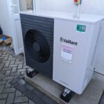 An air-source heat pump unit beside a house wall