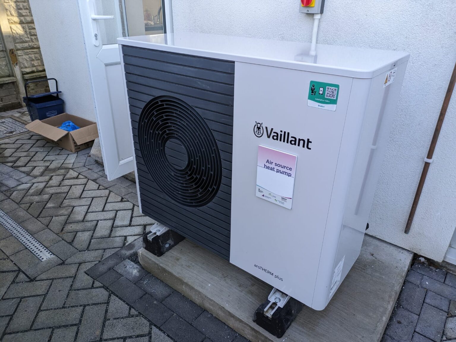 An air-source heat pump unit beside a house wall